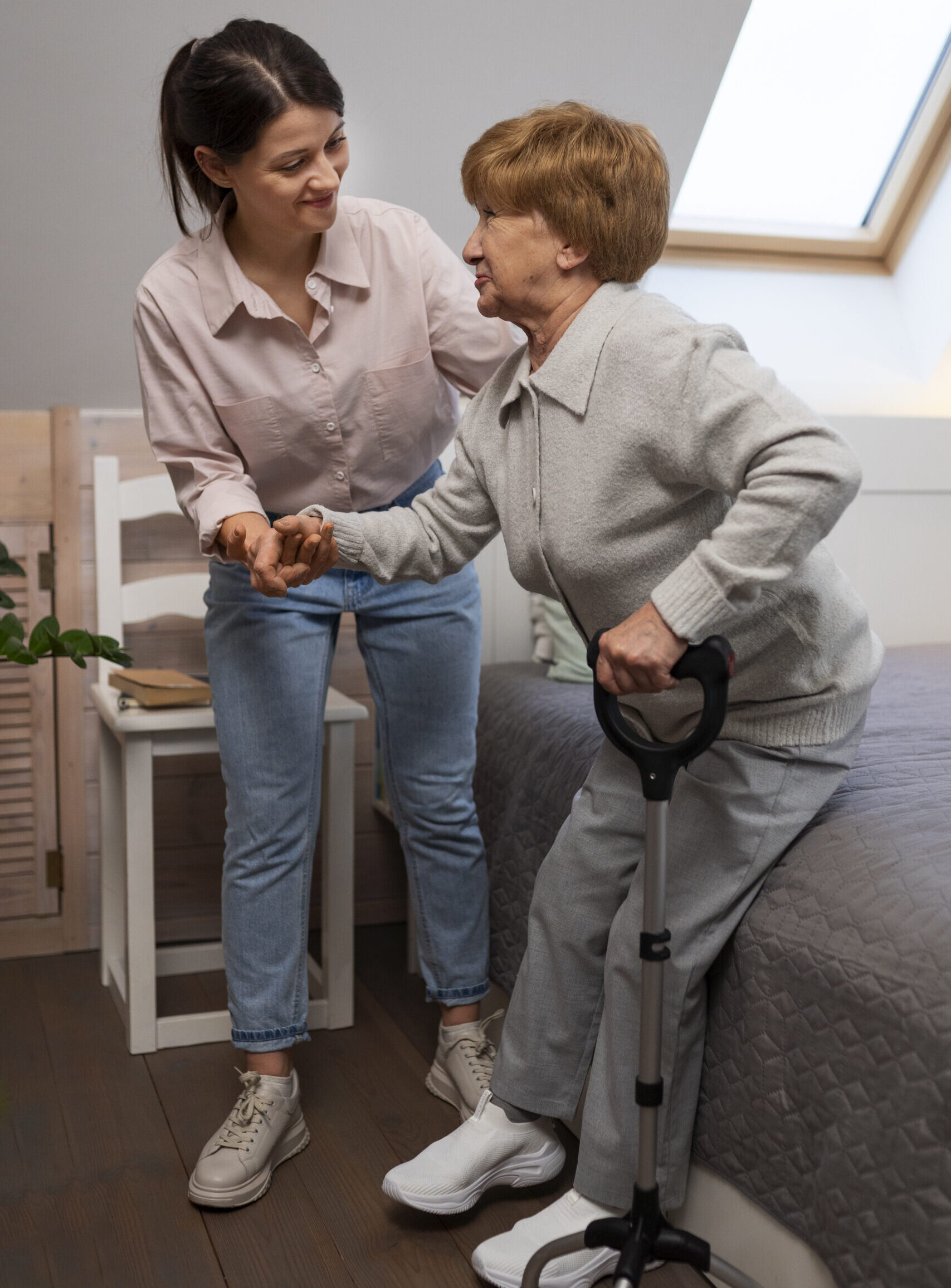 Support worker holding hands with an older person using a walking cane