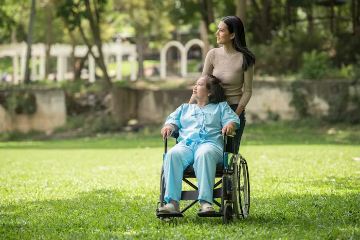 Support worker walking with a person in a wheelchair in a park