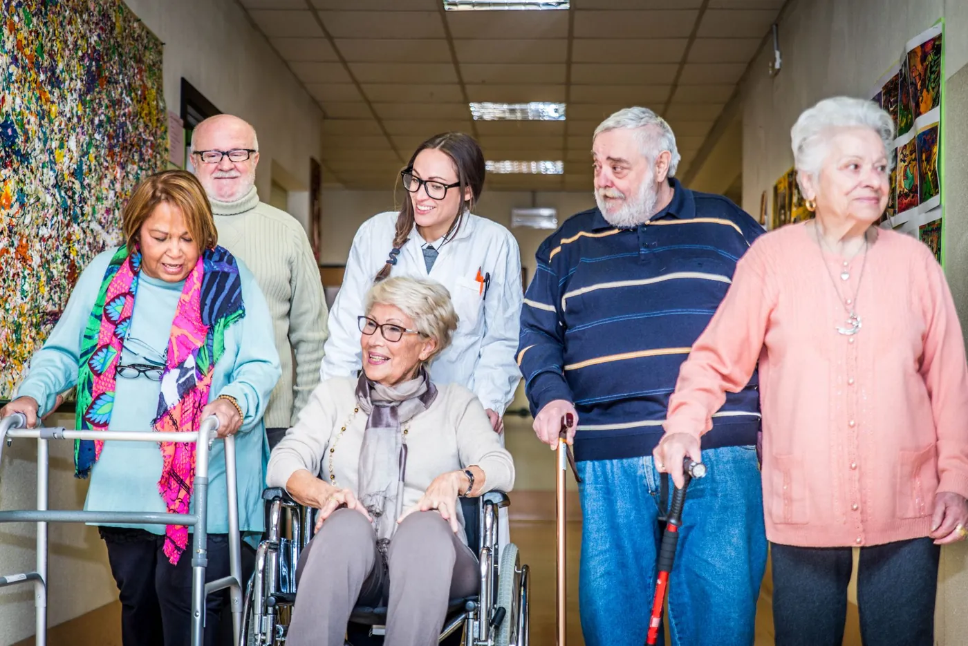 Support worker smiling with a group of older people using a wheelchair, walker and walking canes