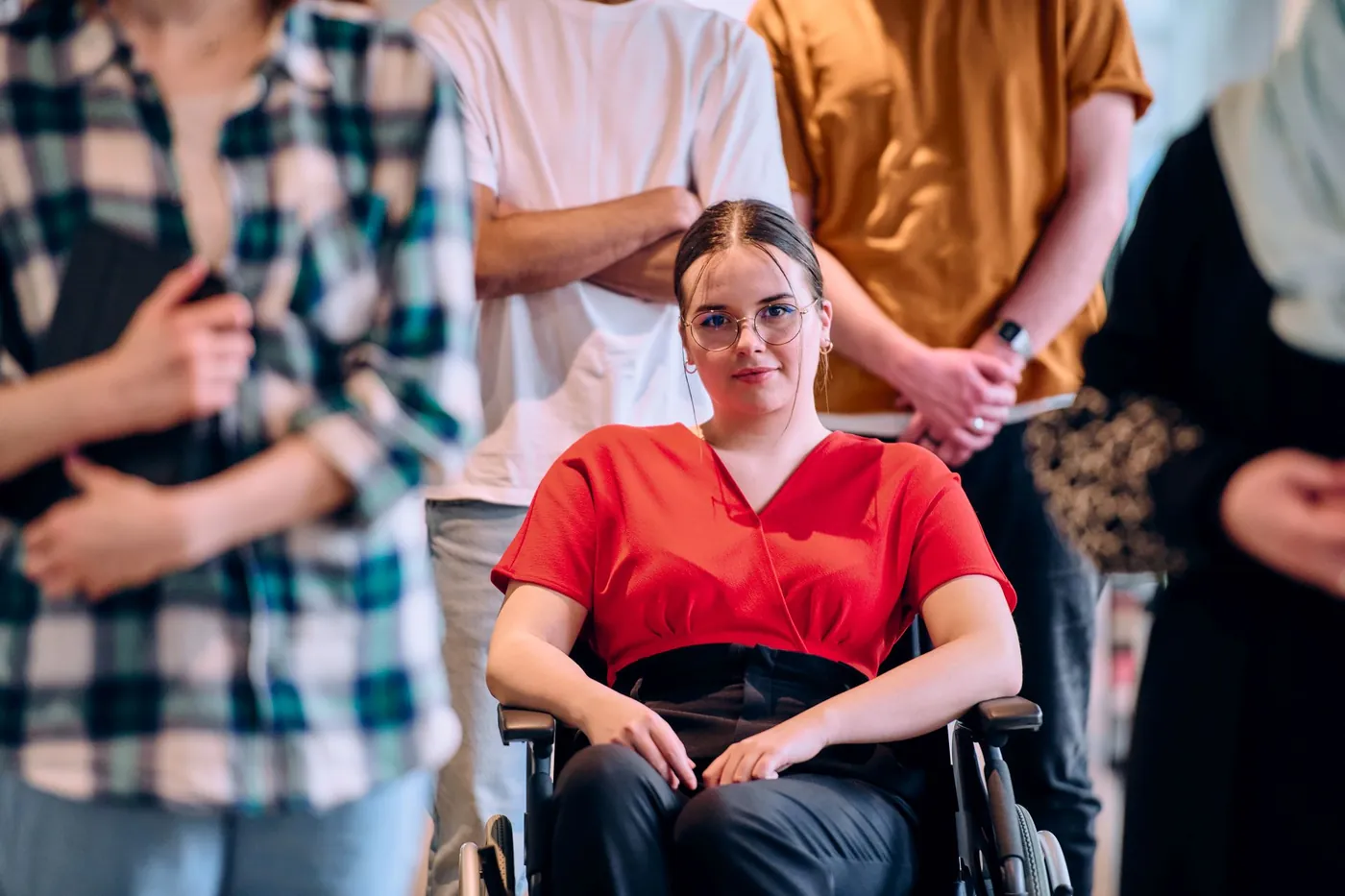 Young woman using a wheelchair, smiling, with her team standing behind her
